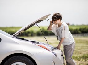 young woman checking under the hood.